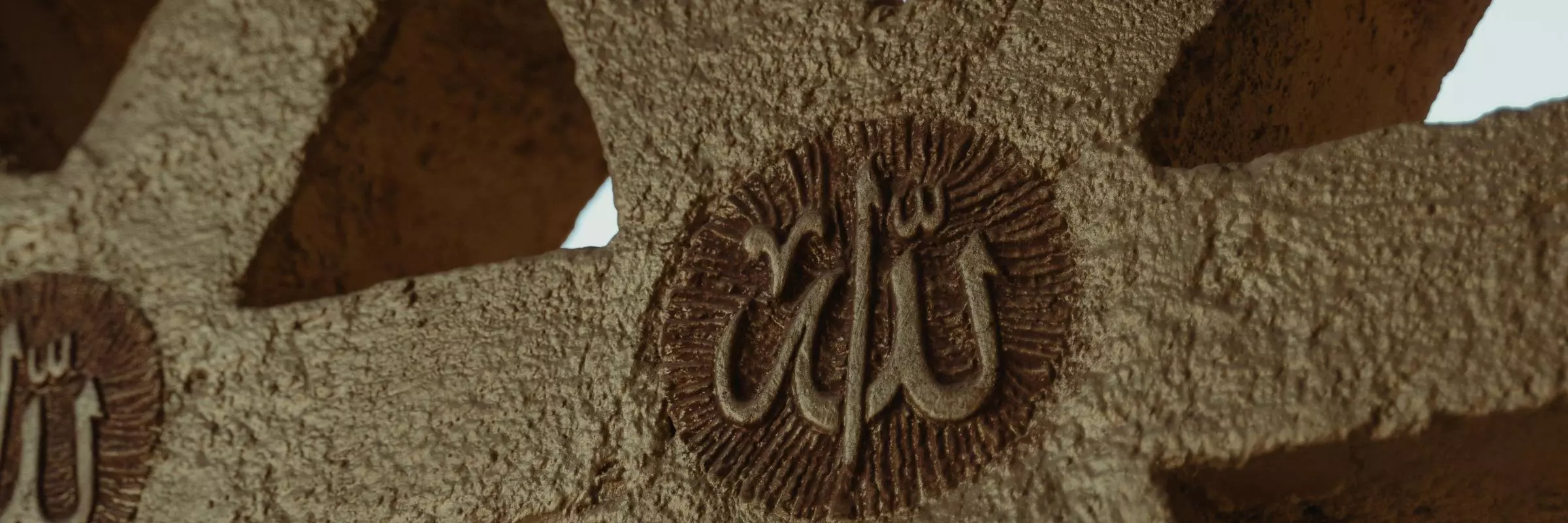 Picture of a concrete, geometric wall with the word "Allah" in Arabic